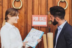 people talking in front of for sale sign