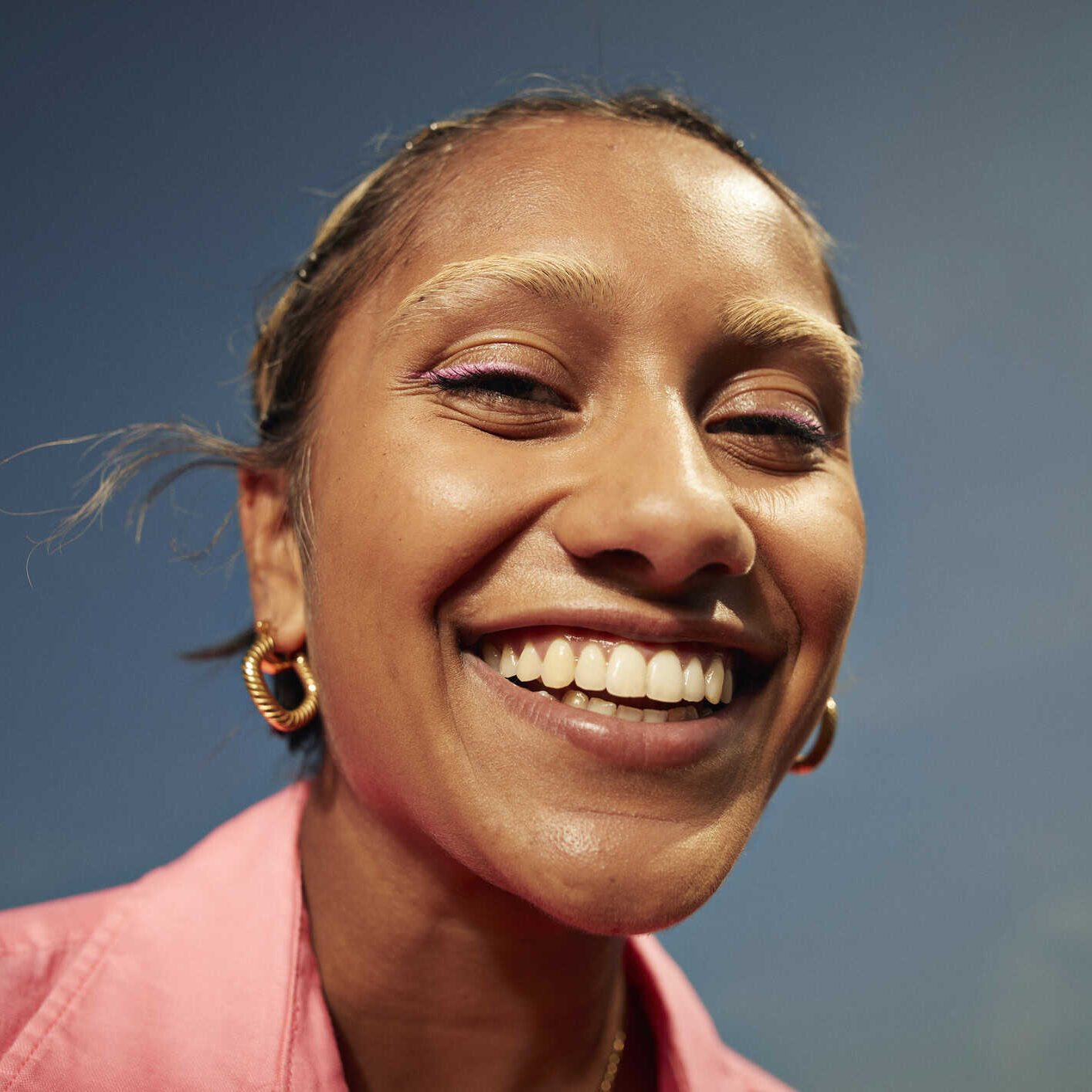 Close-up portrait of happy young woman with toothy smile against sky